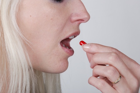  Woman holding a painkiller between fingerの写真素材