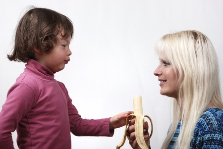 Mom giving a banana to his daughterの写真素材