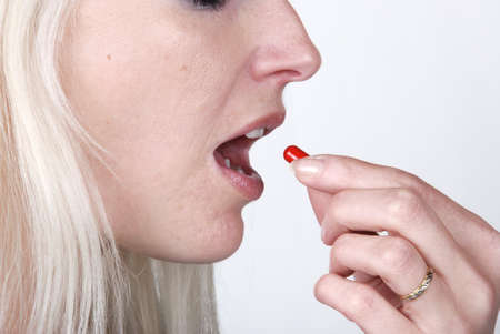  Woman holding a painkiller between fingerの写真素材