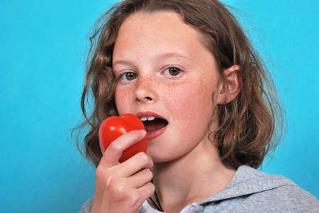 Girl eating a tomatoの写真素材