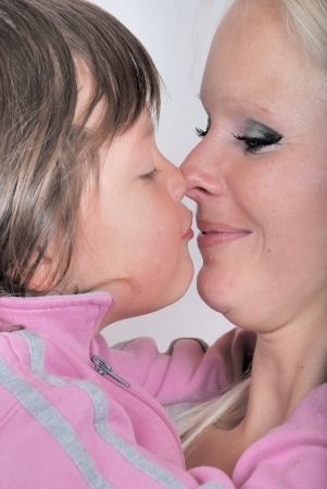 A mother as she receives a kiss from her young daughterの写真素材