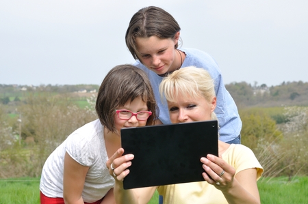 Family sitting on the lawn and using digital tabletの写真素材