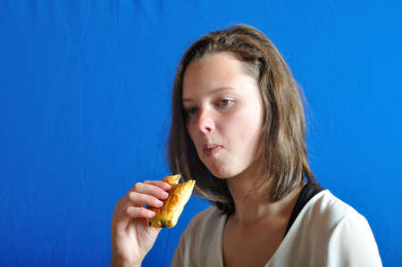 A  teen eating a chocolat bun