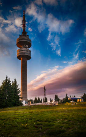 The TV relay tower at Snezhanka Peak rises over a green meadow as the summer sun sets downのeditorial素材