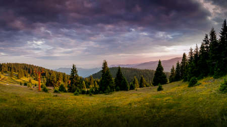 A purple sunset illuminates the cloudy sky over a green mountain meadow in the heart of the Rhodope Mountains in Bulgaria.のeditorial素材