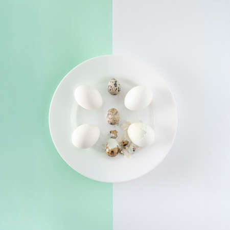White plate with eggs on green and white background. Easter flat lay decoration.