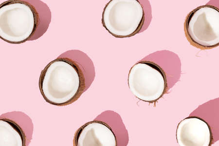 Pattern with ripe coconuts on pink background. Creative summer concept.  Half of coconut in minimal flat lay style. Top View.の写真素材