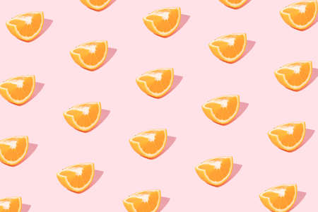 Summer pattern made of orange cut into quarters in a pastel pink background. Trendy creative minimal...