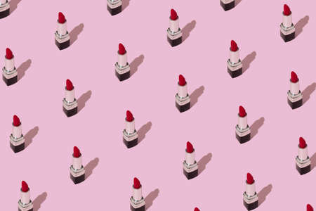 Makeup pattern made with red lipstick in the pastel pink background. Minimal beauty concept, trendy style. Top view, flat lay.の写真素材