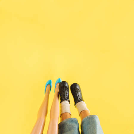 Woman and man legs on a modern yellow background. Blue and black party shoes. Summer creative...