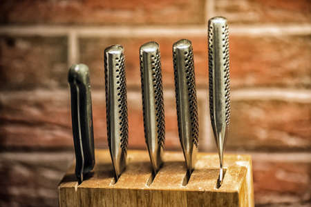 Knifes in the wooden block with brick wall on the backgroundの写真素材