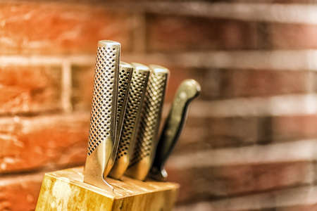 Knifes in the wooden block with brick wall on the backgroundの写真素材