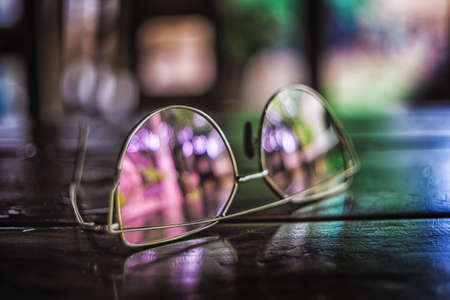 Pictrure of sun glasses on the wooden table with colorfull reflections.の写真素材