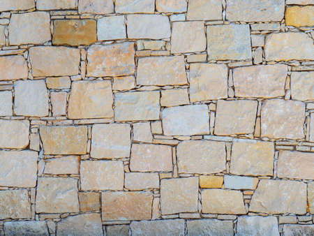 Texture of yellow concrete wall with large and small bricks in mozaic patternの写真素材
