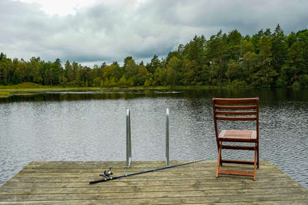 Fishing equipment on seat on lake. Feeder carp rods on wooden pier.の写真素材