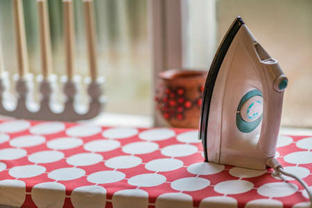 Picture of Electric clothes iron on the ironing board.の写真素材