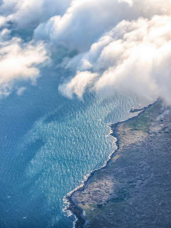 Picture of View from plane window. Aerial top view of sea, sky, clouds and ground.の写真素材
