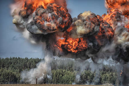 Image of Intense explosion with fire and black smoke and sky in the background