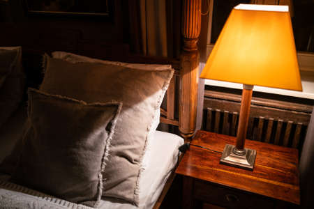 Lamp on a night table next to a bedの写真素材
