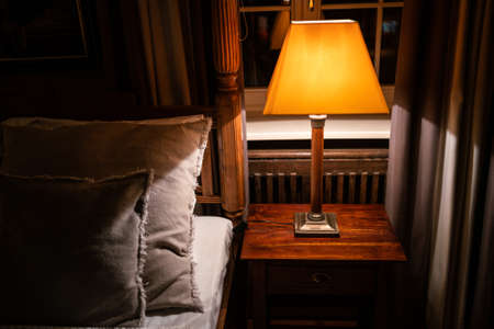 Lamp on a night table next to a bedの写真素材