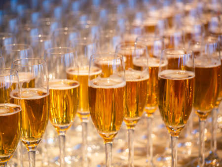 Image of a row of glasses filled with champagne are lined up ready to be servedの写真素材