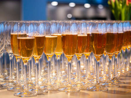Image of a row of glasses filled with champagne are lined up ready to be servedの写真素材