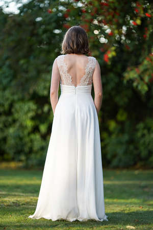 Picture of Beautiful fashionable spring bride from behind on blurred nature background. Floral bridal hairstyle.の写真素材