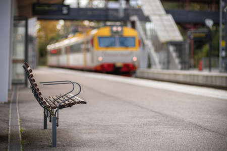 Image of wooden bench on the train station with blurred train on the background