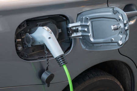 Close-up image of fully electric car power cable socket with charging cable attachedの写真素材