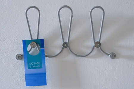 Image of Do Not Disturb Sign on a metal hangers on the wallの写真素材