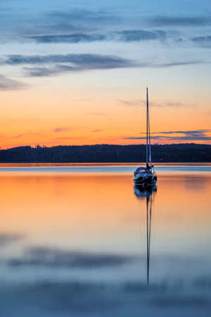 Long exposure picture of boat on the calm lake during sunset or sunriseの写真素材