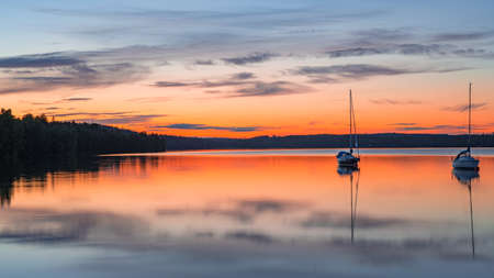Long exposure image of boat on the calm lake during sunset or sunriseの写真素材