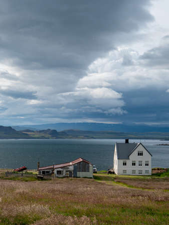 Lonely White Wooden House at coastline in East Iceland with panoramic view and stormy skyの写真素材