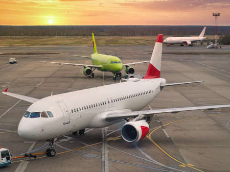 Airplanes near the terminal in an airport at the sunsetの写真素材