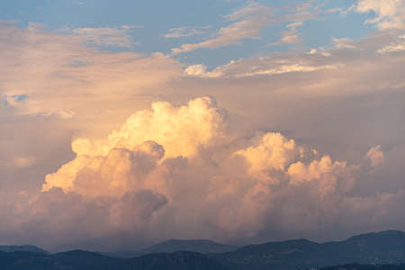 Cloudy orange sunset over the mountains with dramatic cloudsの写真素材