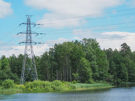 High voltage power lines pylons and electrical cables on a clear blue skyの写真素材