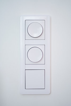 Triple light switch with dimmer on white wallの写真素材