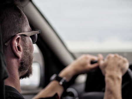 Over the shoulder view of businessman in glasses driving the carの写真素材