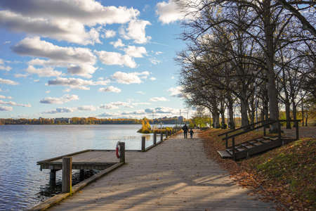 View of wooden path at the autumn lake with father and son walking togetherの写真素材