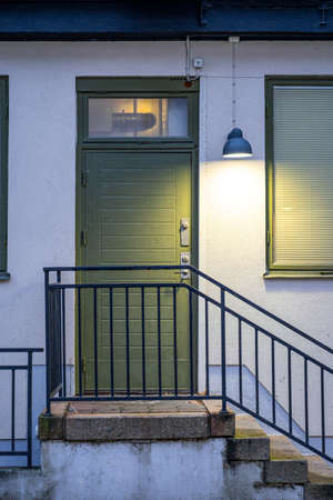 Old worn out green painted wooden door with concrete stairs in front of itの写真素材
