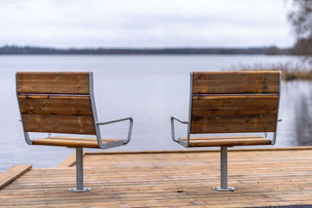Metal with wooden cover modern chairs at the relaxation area in front of the lakeの写真素材