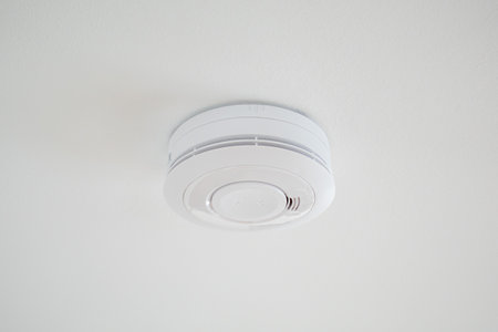 Simple plain fire alarm detector on the white ceiling