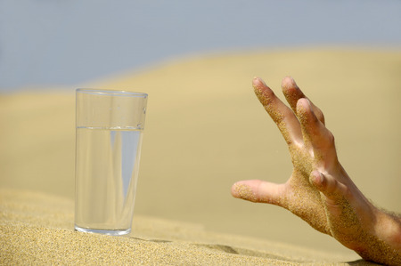 Hand is reaching for a fresh glass of cold water in desert.の写真素材