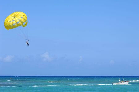 Some people are parasailing over the caribbean sea.の写真素材