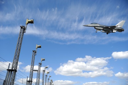 F-16 fighter plane is landing in airport. The sky is blue with white cloudsの写真素材