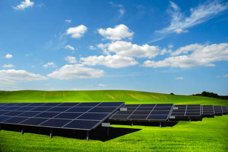 Rows of solar panels and green nature with clouds