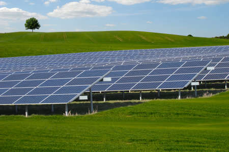 Rows of solar panels and green nature with clouds