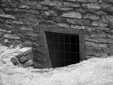 A black and white infrared photograph of a storm drain with a metal fence.の写真素材