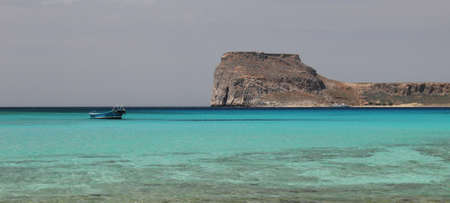A lonely fishing boat on the emerald waves in a shallow tropical Bay, warm ocean.