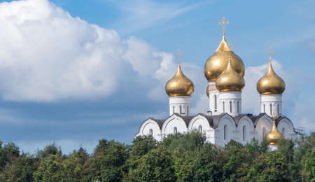 Snow-white Assumption Cathedral with Golden domes of the Russian Orthodox Church on a Sunny summer...